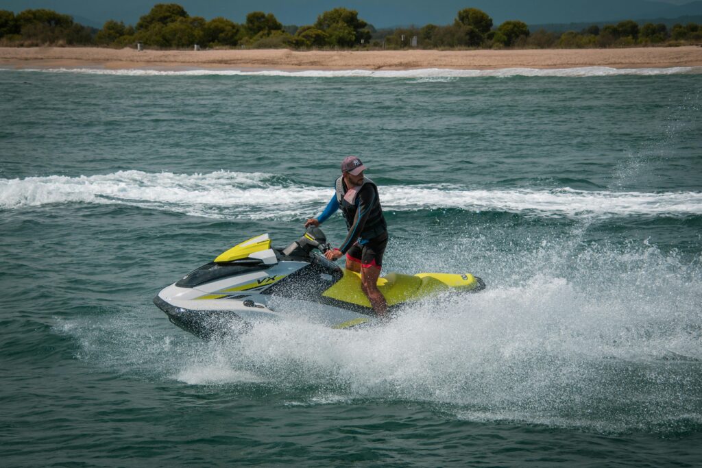 Male enjoying a thrilling ride on a jet ski across ocean waves, showcasing adventure and fun.