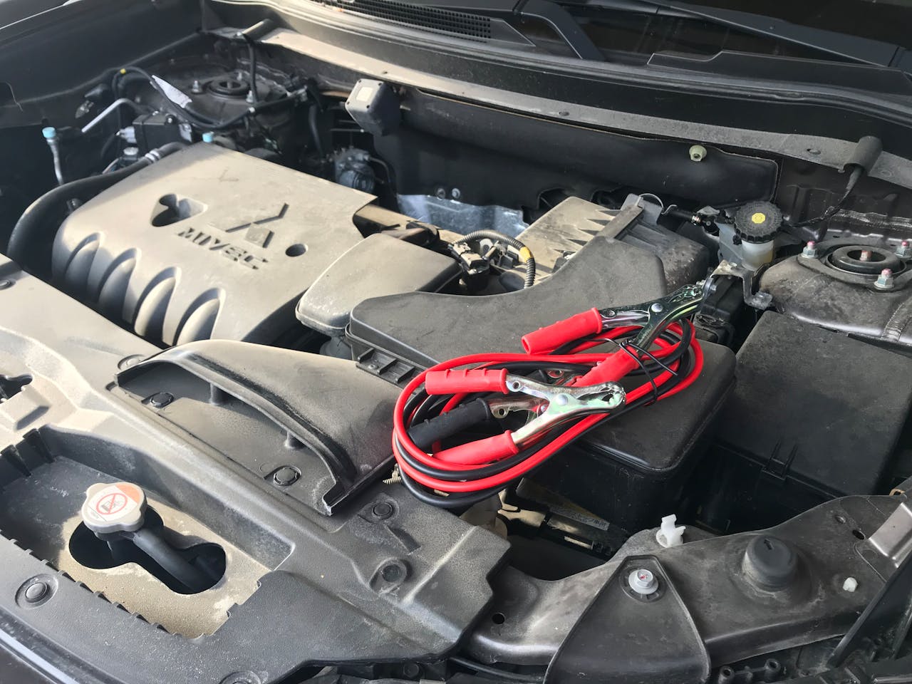 Detailed view of a car engine with red jumper cables, ideal for automotive themes.
